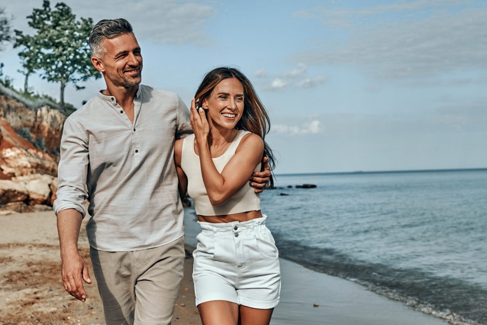 Happy attractive couple walking on beautiful sunny beach - dreamstime_xxl_226882652