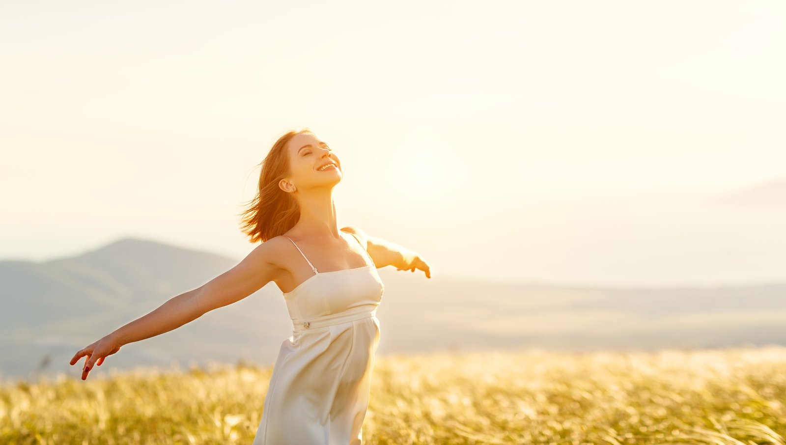 Happy woman standing with her back on sunset in nature with open hands - dreamstime_xxl_94442126